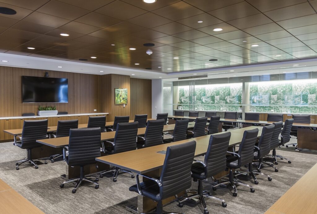 board room with lots of black leather chairs and wood paneling on walls 